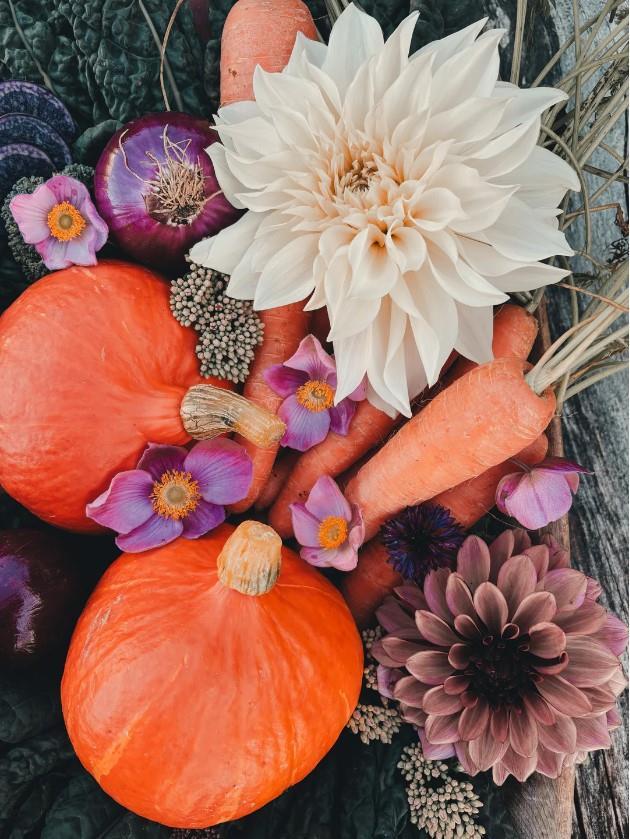 Bilde av blomster, gulrøtter og gresskar.